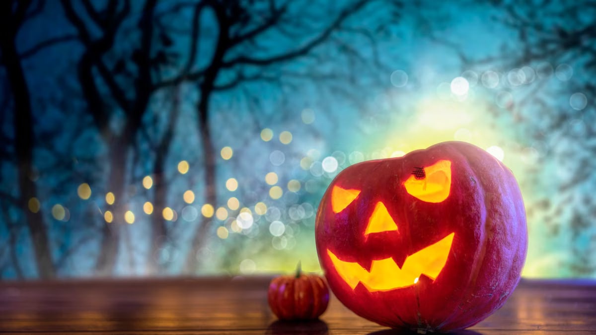 A carved pumpkin jack-o'-lantern glowing on a wooden surface during Halloween night.