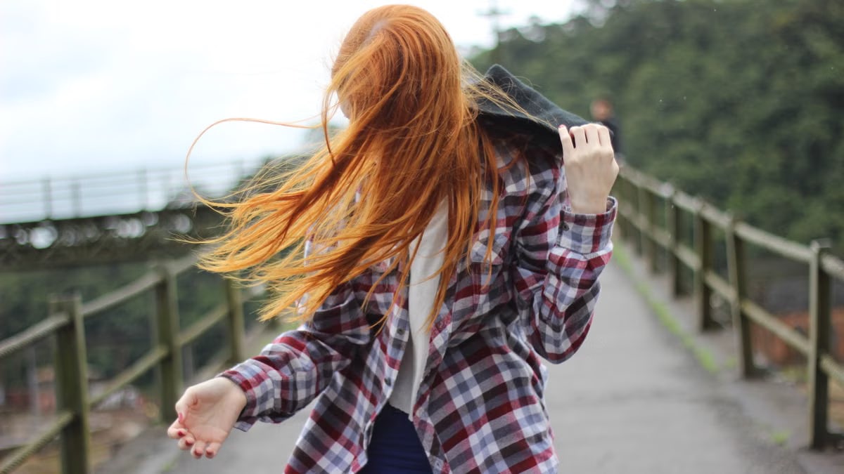 Portrait of a redhead woman outdoors with hair blowing in the wind.